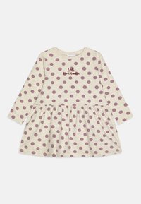 Abito a maniche lunghe in cotone beige con grandi pois bianchi e un ricamo "little heartbreaker" sul petto. Gonna a balze.