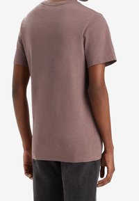 Kortärmad, avslappnad t-shirt i dämpad mauve, tillverkad av mjukt tyg. Har en klassisk rundad halsringning och en enfärgad baksida.