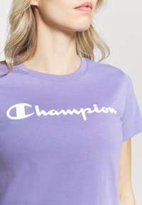 Lila bomull t-shirt med en framträdande vit "Champion"-logga. Kort ärm och rundad halsdesign med en mjuk textur.