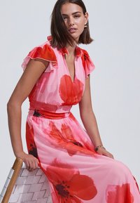 Rózsaszín virágos maxi ruha nagy piros mák mintákkal. Redőzött ujjakkal és karcsúsított derékkal rendelkezik, könnyű, puha anyagból készült.