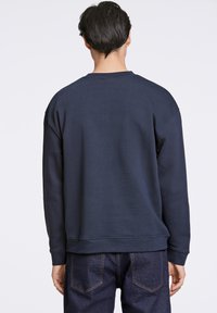 Sudadera azul marino en mezcla de algodón, con cuello redondo, puños acanalados y un corte relajado. Sin patrones ni accesorios visibles.