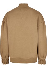 Sweatshirt cărămiziu cu guler înalt, umeri lăsați și manșete strânse. Materialul pare moale și ușor texturat.