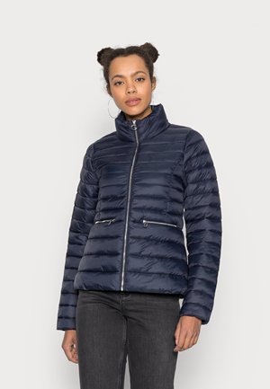 Giacca imbottita blu navy con colletto alto, cuciture orizzontali e due tasche con cerniera. Texture liscia con finitura lucida.