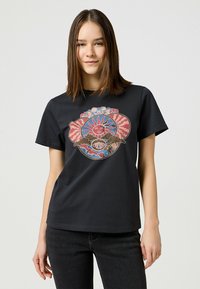 Camiseta de algodón negra con un gráfico colorido de un sol y nubes en el centro. Cuello redondo y mangas cortas. Corte relajado.