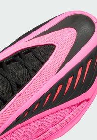 Φωτεινό ροζ και μαύρο αθλητικό παπούτσι με επάνω μέρος από δίχτυ, υφή με ανάγλυφο φινίρισμα, έντονη κορδόνια και τολμηρές γραμμές έμφασης στα πλάγια.