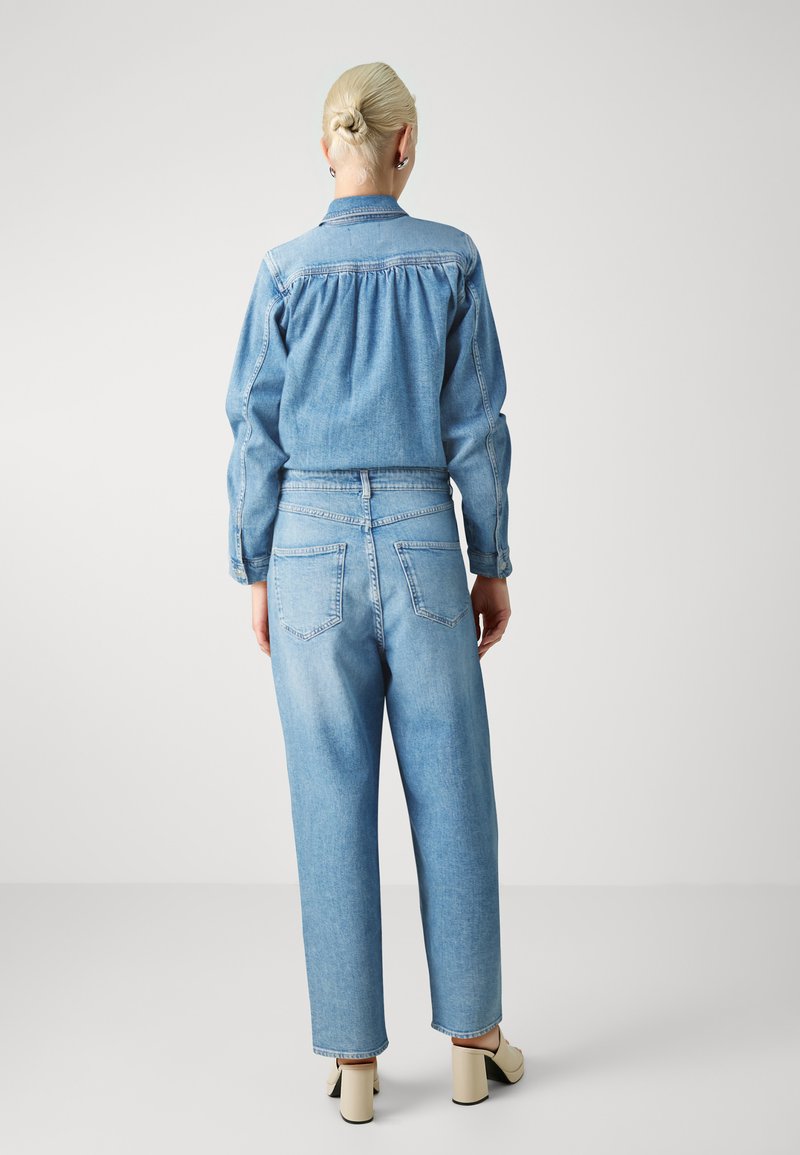 Denim jacket with gathered back detail, paired with high-waisted blue jeans. Both have a light wash and a relaxed fit. Plain, no patterns.