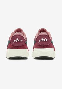 Baskets bordeaux avec une tige en suede texturé, semelles en caoutchouc blanches et logo "Air" sur le talon. Présente des accents verts contrastants.