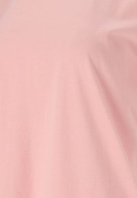 Lichtroze stof met een gladde, iets glanzende afwerking. Het materiaal lijkt zacht en rekbaar, geschikt voor casual kleding.