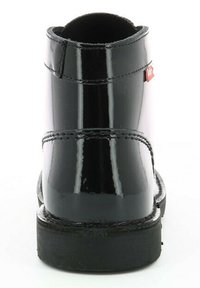 Bottines à cheville en cuir verni noir avec une texture lisse, un bout rond et un accent de logo rouge sur le côté. Semelle en caoutchouc noir robuste.