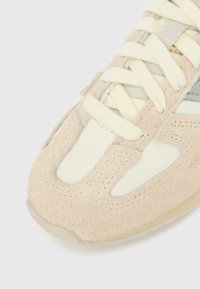 Beežid seemisnahast vabaajajalatsid kreemika võrgust detailidega, millel on tekstureeritud pealiskihid, lamedad paelad ja helekummikummist tald.