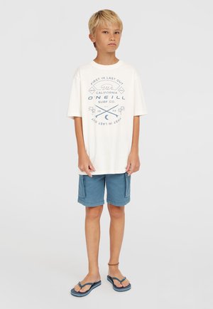 Weißes Baumwoll-T-Shirt mit blauer Druckgrafik, lockere Passform. Hellblaue Shorts mit seitlichen Taschen, flacher Saum. Schwarze Flip-Flops mit blauen Akzenten.