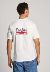 Bílý bavlněný tričko s krátkými rukávy, na zadní straně s potiskem vlajky Spojeného království a logem "Pepe Jeans" v námořnické modré a červené barvě.