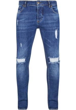 Jeans ajustados de denim azul oscuro, con detalles desgastados y desgarros en las rodillas. Diseño clásico de cinco bolsillos con cremallera y presillas para cinturón.