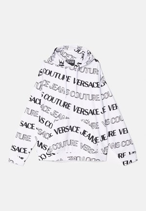 Fehér kapucnis pulóver, amelyen ismétlődő fekete szöveg látható "VERSACE" és "JEANS COUTURE" felirattal. A pulóver kapucnija húzózsinórral ellátott, és elöl zseb található.