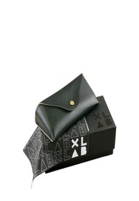 Černá kožená taštička se zlatým knoflíkem, umístěná na černé krabičce se geometrickými vzory. Měkká textura, elegantní design, kompaktní tvar.
