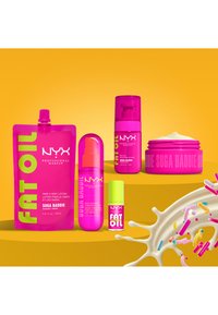Felroze NYX Professional Makeup producten waaronder lotion, lichaamsolie en crème, weergegeven tegen een gele achtergrond met kleurrijke sprinkels.