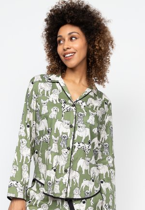 Green pajama top featuring a pattern of various dogs in black and white. It has a collar, button-up front, and long sleeves with black trim.