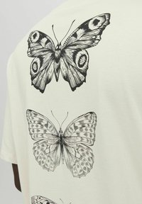 White t-shirt featuring three black butterfly illustrations on the back, showcasing detailed wings with various patterns and textures.