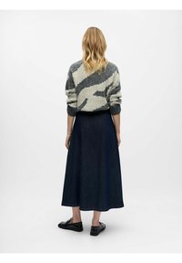 Pull en maille gris et crème avec texture côtelée ; jupe longue en denim bleu marine ; chaussures noires à petit talon. Vue de dos sur fond blanc.
