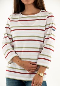Camicia a maniche lunghe a righe in bianco, rosso, verde e rosa pallido. Tessuto di cotone morbido, scollo ampio, maniche di dimensioni medie e un'etichetta sulla manica.