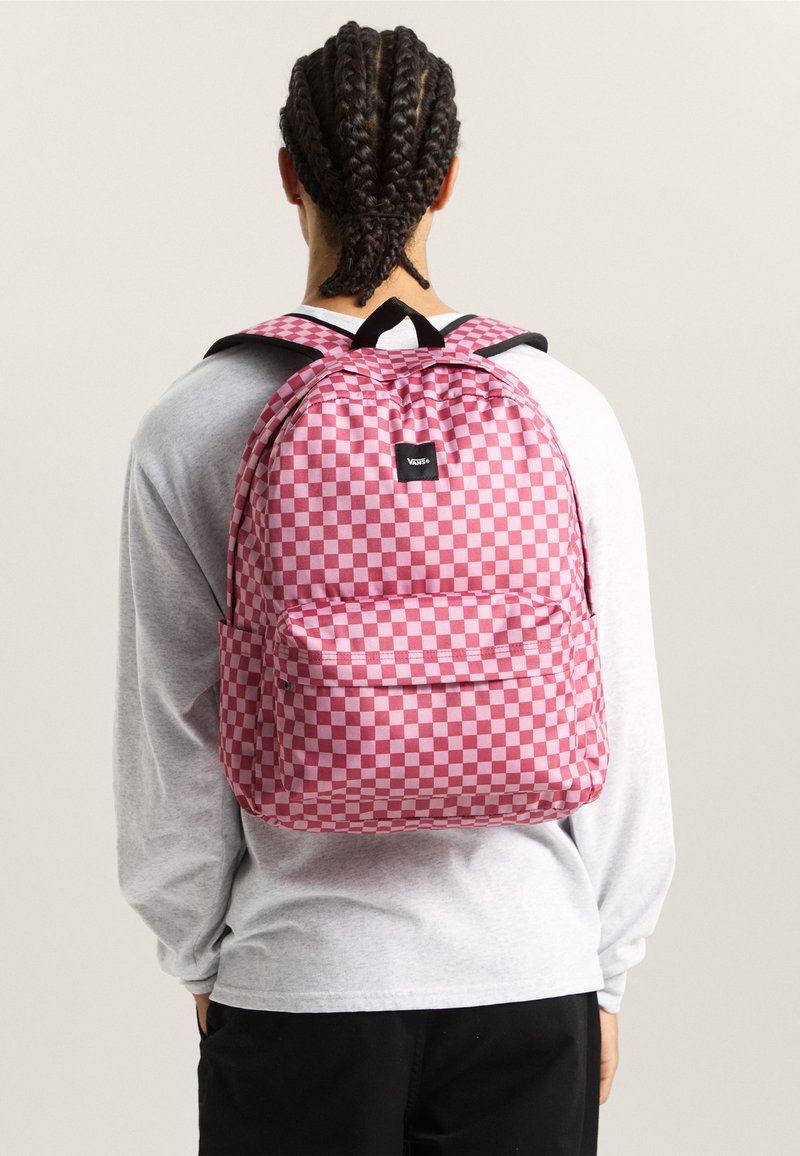 Mochila a cuadros rojos y rosas con correas negras y logo, con un bolsillo delantero y respaldo acolchado para mayor comodidad.