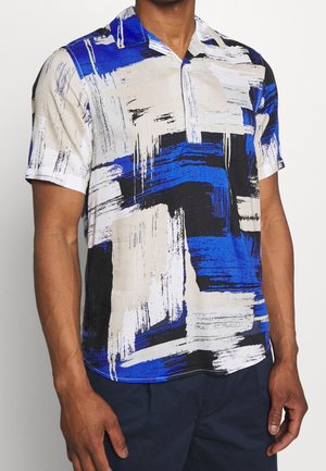 Chemise à manches courtes en mélange de blanc, bleu et noir avec des motifs de coups de pinceau ; design de col et texture de tissu lisse.