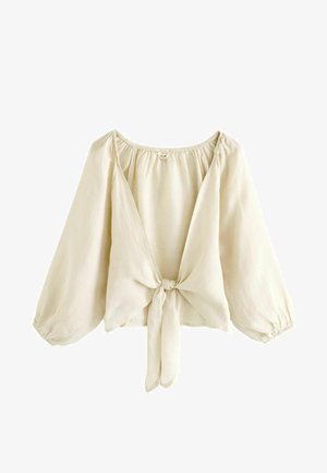 Light beige blouse made of lightweight fabric, featuring a deep V-neck, puff sleeves, and a tie closure at the front. Smooth texture.