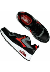 Schwarze Sneakers mit roten und grauen Akzenten, ausgestattet mit einem Mesh-Obermaterial, Schnürverschluss, gepolstertem Innenfach mit der Bezeichnung "Memory Foam" und sichtbarem Luftpolster.