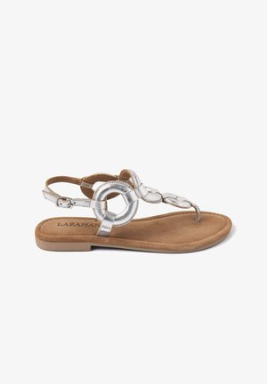 Zilverkleurige metallic platte sandalen met een cirkelvormig accentontwerp, voorzien van een tan faux suede binnenzool en een verstelbare enkelband.