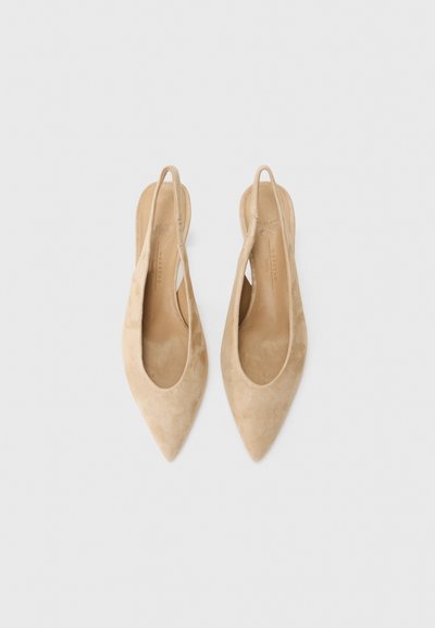 Beige suede slingback heels with a pointed toe and open sides, featuring a smooth texture and a minimalist design. Flat leather insoles.