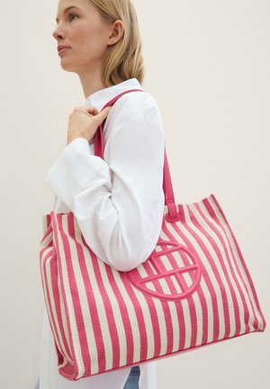 Sac fourre-tout rayé en crème et rose, avec un design de découpe ronde. Fabriqué en tissu texturé avec des larges sangles pour le transport.