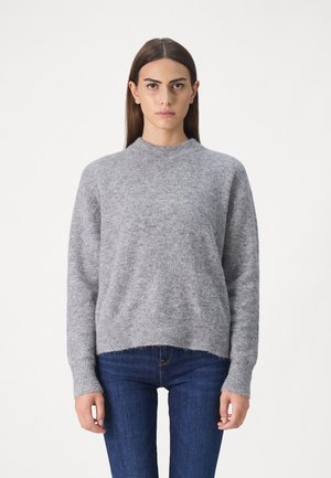 Grau gestrickter Pullover mit rundem Ausschnitt, lockerer Passform und gerippten Bündchen und Saum. Weiche Textur und leichtes Erscheinungsbild. Kombiniert mit dunklen Jeans.