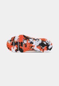 Sole of athletic shoe with textured grip, featuring a camouflage pattern in orange, black, and white.