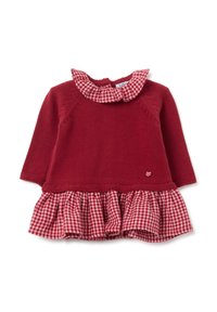 Robe tricotée rouge avec jupe à volants en vichy, avec un col évasé et un petit accent en forme de cœur. Manches longues, corsage texturé avec des détails de coutures.