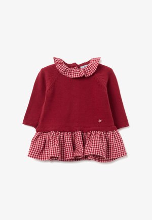 Robe tricotée rouge avec jupe à volants en vichy, avec un col évasé et un petit accent en forme de cœur. Manches longues, corsage texturé avec des détails de coutures.