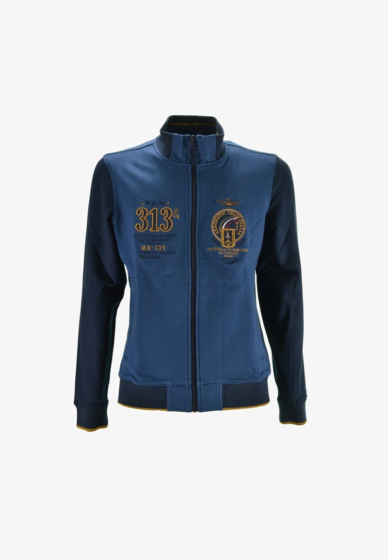 Giacca blu con zip, caratterizzata da dettagli ricamati, inclusi numeri e loghi. Presenta un colletto alto, polsini a coste e una texture morbida.