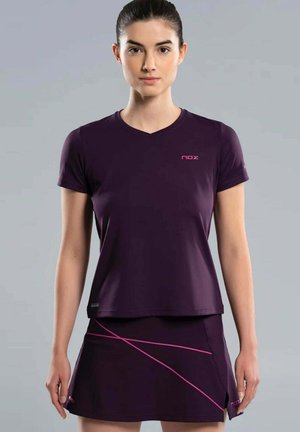 Femme portant une tenue de sport violet foncé composée d'un haut à manches courtes et d'une jupe avec des lignes diagonales roses sur la jupe.