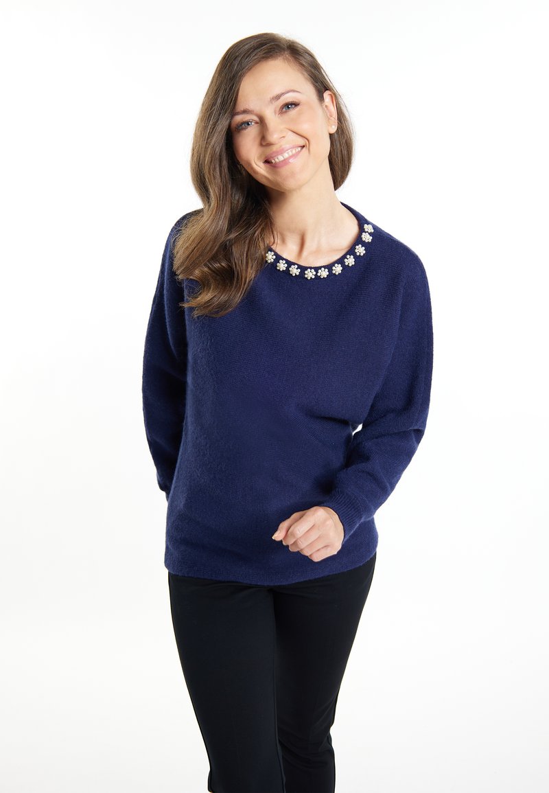 Navyblauer Pullover mit rundem Halsausschnitt, verziert mit weißen Blumenakzenten. Weicher Stoff, lockere Passform und lange Ärmel.