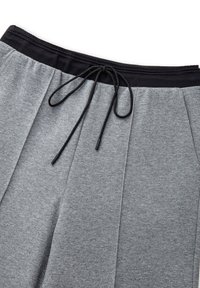 Pantaloni della tuta grigi con cintura elastica nera e lacci neri, mostrati distesi su uno sfondo bianco.