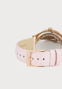 Reloj de acero inoxidable color oro rosa con correa de cuero rosa claro que presenta una textura de cocodrilo y agujeros rectangulares, asegurado con una hebilla.