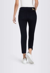 Jeans en denim noir avec une coupe slim, longueur cheville, dotés de poches arrière et d'un motif brodé coloré au-dessus de la poche droite.