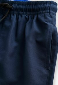 Shorts da jogging blu navy realizzati in tessuto morbido, dotati di una vita elastica con cordoncino, tasche laterali e superficie liscia.