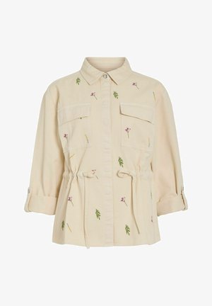 Béžová bunda na zapínanie na gombíky s golierom, dvoma náprsníkovými vreckami, opaskami v páse, vyhrnutými rukávmi a malými vyšívanými zelenými listami a ružovými kvetmi.