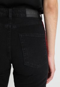 Černé džíny z denimu s vysokým pasem, s efektivním skladem na zadní kapse a koženým štítkem na pase. Texturovaná tkanina, slim fit.