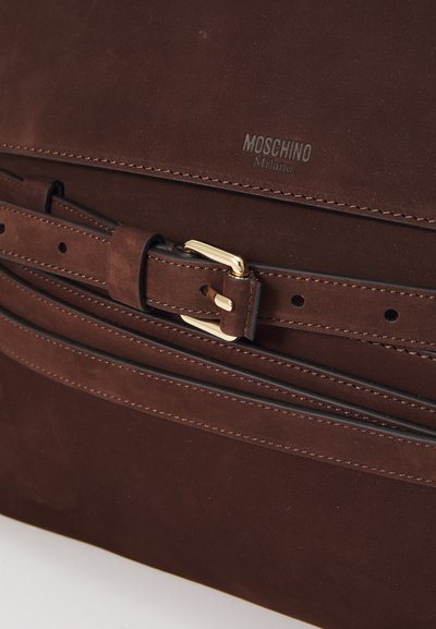 Pruun nahast kott, millel on õmmeldud detailid, kuldne pandla ja "Moschino Milano" logo reljeefselt pinnale pressitud.