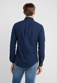 Námořnická košile s dlouhým rukávem vyrobená z bavlny, s límečkem na knoflíky, který má jemně zaoblený spodní lem a detaily knoflíkových manžet.