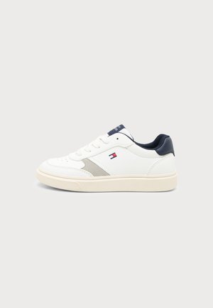 Λευκό low-top αθλητικό παπούτσι με ναυτικό μπλε λεπτομέρειες, μπεζ σόλα, κορδόνια και μικρό κόκκινο, λευκό και μπλε λογότυπο στην πλευρά.