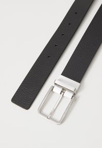 Cintura in pelle nera con superficie texturizzata, dotata di una fibbia rettangolare in argento e numerosi fori di regolazione lungo la fascia.