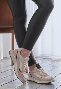 Scarpe da atletica leggere con una combinazione di materiali rosa e beige. Presentano pannelli in rete, una suola testurizzata e dettagli neri.