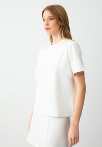 Witte top met korte mouwen, voorzien van een ronde halslijn en verspreide kleine strass-steentjes, gemaakt van soepel materiaal met een comfortabele pasvorm.